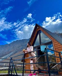 a woman standing on the balcony of a cabin at Kazbegi Kuro Cottages in Kazbegi