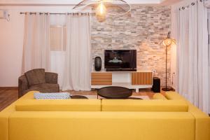 a living room with a yellow couch and a tv at Maison Meublée *WIFI* *CLIM* *PARKING* in Douala
