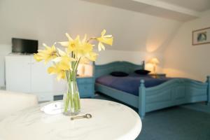 a vase of yellow flowers on a table in a bedroom at Boutique Hotel Gut Tribbevitz in Neuenkirchen auf Rugen