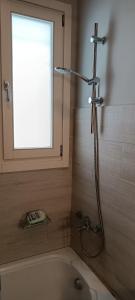 a shower in a bathroom with a tub and a window at Andros Guesthouses in Andros