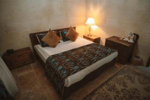 a bedroom with a large bed with pillows and a lamp at Hu of Cappadocia - Special Class in Uchisar