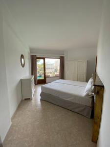 a bedroom with a bed and a large window at Hostal Palmaria in Cala Santanyi
