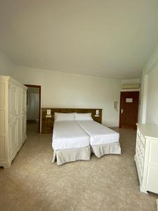 a bedroom with a large white bed in it at Hostal Palmaria in Cala Santanyi