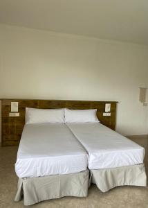 a large bed with white sheets and pillows at Hostal Palmaria in Cala Santanyi