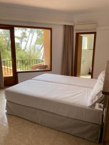 a bedroom with a large bed and a balcony at Hostal Palmaria in Cala Santanyi