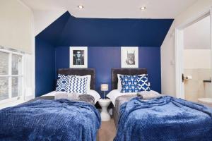 two beds in a room with blue walls at The Cozy Central Bath Duplex in Bath