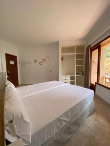 a bedroom with a large white bed and a window at Hostal Palmaria in Cala Santanyi