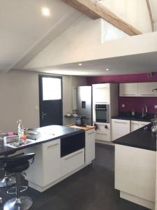 a large kitchen with white cabinets and black counter tops at Le Breuil in Amboise