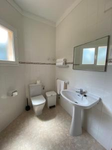a white bathroom with a toilet and a sink at Hostal Palmaria in Cala Santanyi
