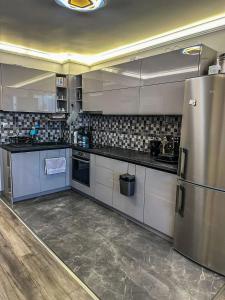 La cuisine est équipée d'un réfrigérateur et de placards en acier inoxydable. dans l'établissement APARTMENT ROYAL ASENOVGRAD, à Asenovgrad