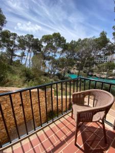 a chair on a balcony with a view of the water at Hostal Palmaria in Cala Santanyi