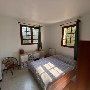 1 dormitorio con 1 cama, 1 silla y 2 ventanas en Villa La Louette, 100m centre-village, piscine h-sol, proche mer, en Saint-Cyr-sur-Mer