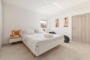a white bedroom with a large bed and a window at Bright Apartment in Koper
