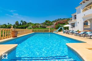 a swimming pool with a slide in front of a house at Villa Perla by Abahana Villas in Teulada