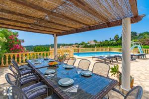 a patio with a table and chairs and a pool at Villa Perla by Abahana Villas in Teulada