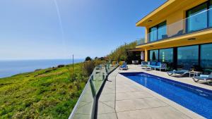 a house with a swimming pool next to the ocean at Eden Sun - A Modern Luxury Villa with a Panoramic View in Prazeres