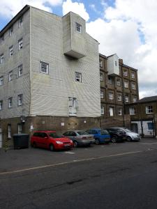 a building with cars parked in a parking lot at Apartment in Historic Mill, near Dover Port in Kent