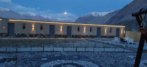 a white building with mountains in the background at Eden Resort Nubra in Hundar