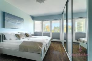 a bedroom with a large white bed and windows at Your Holidays Playa Baltis in Międzyzdroje