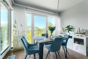 a dining room with a table and blue chairs at Your Holidays Playa Baltis in Międzyzdroje