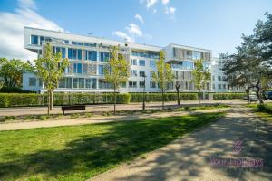 a large white building with trees in front of it at Your Holidays Playa Baltis in Międzyzdroje
