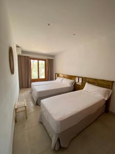 a hotel room with two beds and a window at Hostal Palmaria in Cala Santanyi