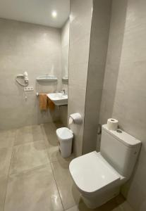 a white bathroom with a toilet and a sink at Hostal Palmaria in Cala Santanyi