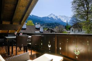 een balkon met tafels en stoelen en uitzicht op de bergen bij Chalet Vierjahreszeiten in Garmisch-Partenkirchen