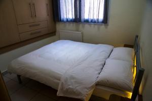 Schlafzimmer mit einem Bett mit weißer Bettwäsche und einem Fenster in der Unterkunft Elpida's houses 1 Private parking Near city centre in Thessaloniki