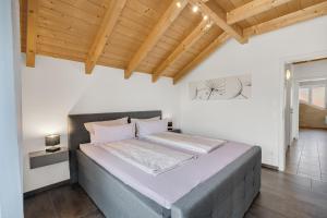 una camera con un grande letto e un soffitto in legno di Cosy Home Allgäu - modern und gemütlich a Haldenwang