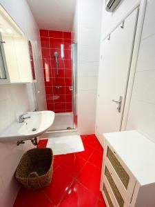 a bathroom with a sink and a shower with red tiles at Basement Studio Bed&Breakfast in Punat