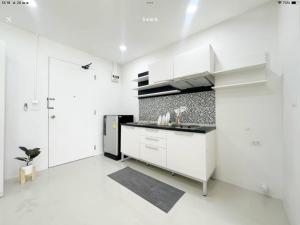 a white kitchen with a sink and a refrigerator at เดอะสแควร์ คอนโดมิเนียม in Ban Phlu Yai