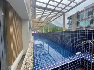 a swimming pool in a building with blue tiles at เดอะสแควร์ คอนโดมิเนียม in Ban Phlu Yai