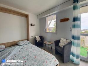 a bedroom with a bed and a chair and a window at Men Er Mor in Quiberon