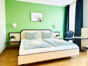 F-1010 Strandhaus Mönchgut Bed&Breakfast DZ 28 Terrasse strandnah, inkl Frühstück في لوبه: غرفة نوم بسرير مع جدار أخضر
