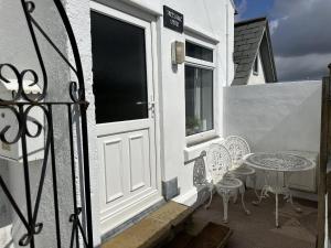 a patio with a white door and a table and chairs at Immaculate 2-Bed Lodge in Hayle in Hayle
