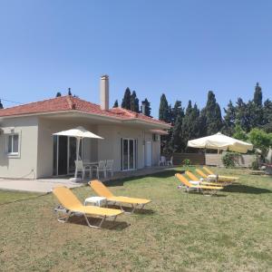 a group of lounge chairs and umbrellas in a yard at Sea Breeze Villa in Rethymno