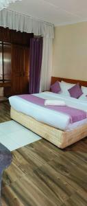 two twin beds in a room with wooden floors at Kafka Gardens in Kisumu