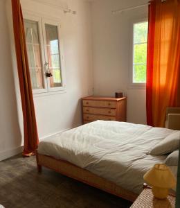 a bedroom with a bed and a dresser and two windows at Maison de village in Valle-di-Rostino