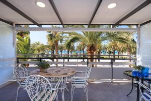 a patio with a table and chairs and palm trees at UHC RODAS APARTMENTS in Salou