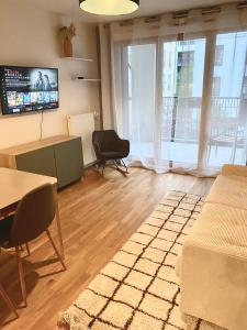 uma sala de estar com uma mesa e cadeiras e uma televisão em Sérénité totale : appartement ensoleillé em Clichy