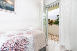 a white bedroom with a bed and a balcony at Apartman Oly in Rovinj