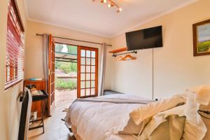 a bedroom with a bed and a tv on the wall at Cinzaco Dullstroom in Dullstroom