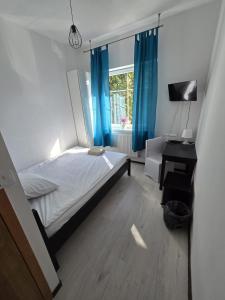 1 dormitorio con 1 cama y una ventana con cortinas azules en Średzka Korona, en Środa Śląska