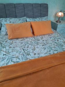 uma cama com duas almofadas cor-de-laranja em Cozy Apartment em Alūksne