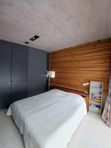 1 dormitorio con cama blanca y pared de madera en Ihastuttava vierasmaja omalla sisäänkäynnillä., en Sotkamo