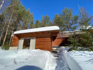 Cabaña de madera con nieve encima en Ihastuttava vierasmaja omalla sisäänkäynnillä., en Sotkamo