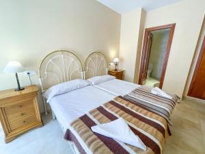 1 dormitorio con 1 cama grande con manta a rayas en Apartament Peñíscola Centro Llandels 3000, en Peñíscola