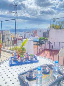 - une table avec des assiettes et des bouteilles d'eau sur le balcon dans l'établissement Zoco Riad, à Tanger