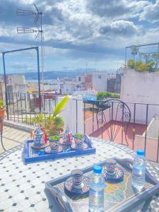 una mesa con platos y botellas de agua en el balcón en Zoco Riad, en Tánger